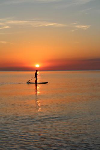 a man on a paddle board in the water at sunset at Haus Strandleben in Hohwacht