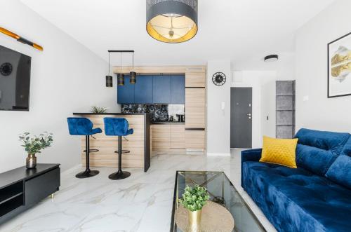 uma sala de estar com um sofá azul e uma cozinha em Lumina apart Manufaktura em Lódź
