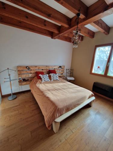 Un dormitorio con una cama grande en una habitación con techos de madera. en Grande maison familiale, en Serres-Gaston