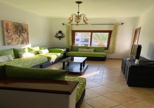 - un salon avec des canapés verts et une télévision dans l'établissement Mi Casa Jardins de Cabo Negro, à Cabo Negro