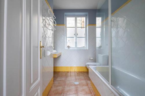 een badkamer met een bad, een toilet en een raam bij Céntrico Ático frente al Mar in Vigo