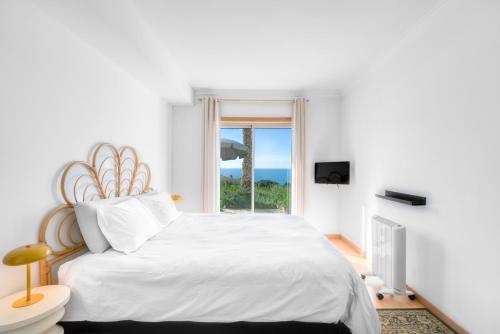 ナザレにあるBig Wave Front Row - One Bedroomの白いベッドルーム(大型ベッド1台、窓付)