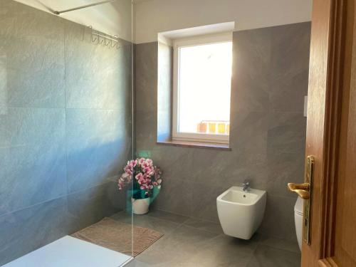 a bathroom with a toilet and a vase of flowers at Casa Pallanch in Fai della Paganella