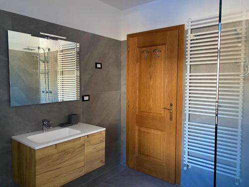 a bathroom with a sink and a wooden door at Casa Pallanch in Fai della Paganella