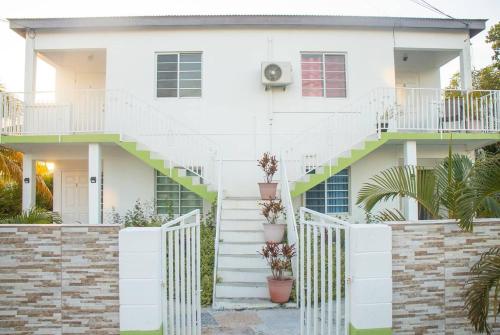 a white house with stairs and a fence at Lovely 2-Bedroom Apt Sleeps 3 Warm & Cosy in Belmont