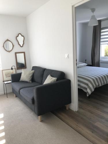 ein Wohnzimmer mit einem Sofa und einem Bett in der Unterkunft Un sejour a Cabourg in Cabourg