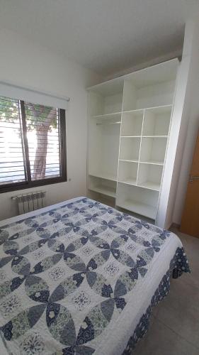 a bedroom with a bed and a window and shelves at S1 Cálido departamento para conocer Mendoza in Godoy Cruz
