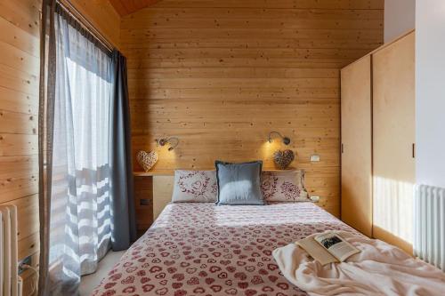 a bedroom with a bed with a wooden wall at Baita sulle piste in Valmalenco in Chiesa in Valmalenco