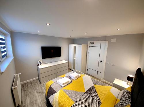 a bedroom with a yellow and white bed and a tv at Private Room in Exclusive Apartment in Aberdeen