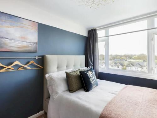 Schlafzimmer mit blauen Wänden und einem Bett mit Fenster in der Unterkunft Pass the Keys Eton Penthouse with Amazing Castle River Views in Windsor