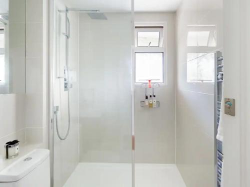 a white bathroom with a shower and a sink at Pass the Keys Eton Penthouse with Amazing Castle River Views in Windsor