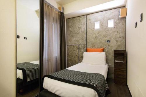 a small room with a bed and a mirror at Casa alle Colonne by Hotel Ancora in Verbania