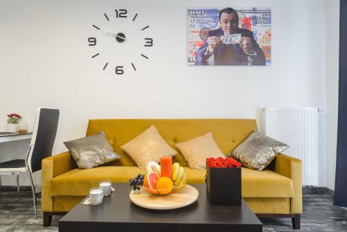 a living room with a yellow couch and a clock at Lumina apart Manufaktura in Łódź