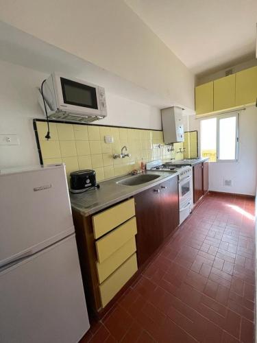 eine Küche mit einem weißen Kühlschrank und einer Mikrowelle in der Unterkunft 2 AMBIENTES A METROS DE LA PLAYA LA PERLA in Mar del Plata
