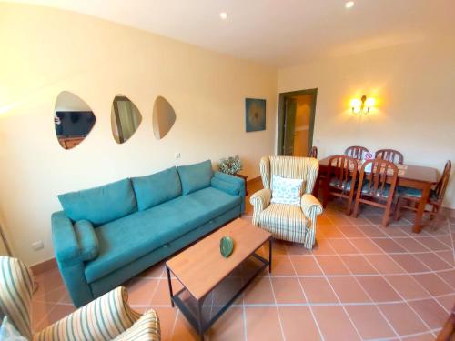 een woonkamer met een blauwe bank en een tafel bij Plaza Andalucía Edificio Salvia 2-6 pax in Monachil