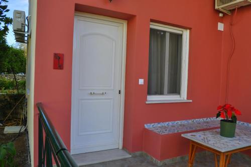 a white door on a red wall with a table at MagnoliaHouse 1 in Preveza