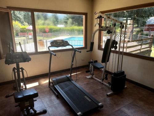 - une salle de sport avec des équipements d'exercice et une vue sur la piscine dans l'établissement Aparts chalet Alquimia, à Lago Puelo
