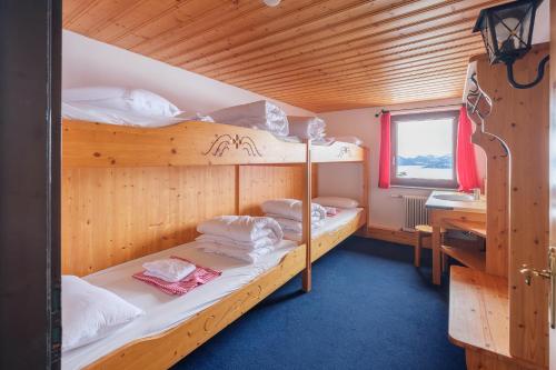 2 Etagenbetten in einem Holzzimmer mit einem Schreibtisch in der Unterkunft Berggasthof Hörnerhaus in Bolsterlang