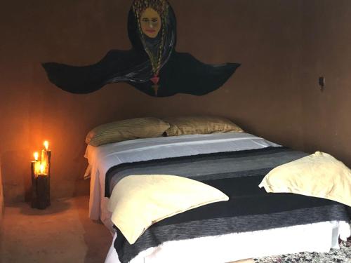 a bedroom with a bed with a painting on the wall at Sahara Authentic Berber Camp in Mhamid