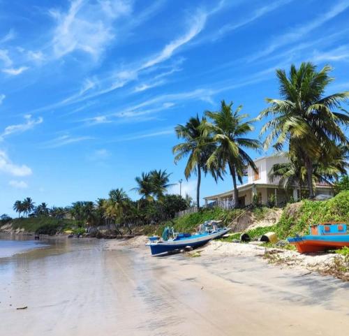 Chalet no paraíso في مراكاجو: يوجد قاربان على الشاطئ مع أشجار النخيل