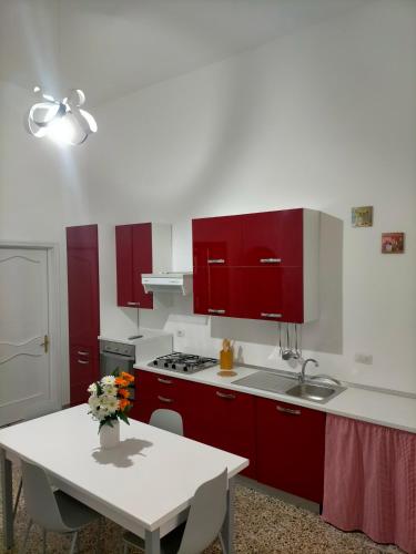 una cocina con armarios rojos y una mesa blanca en Casa Nonna Lucetta, en Campi Salentina