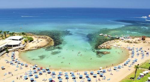 ein Strand mit Sonnenschirmen und Menschen im Wasser in der Unterkunft Anastasia Waterpark Beach Resort in Protaras