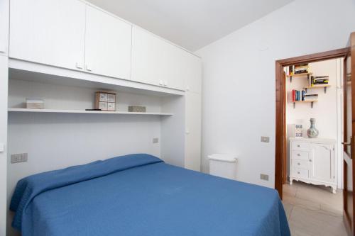 um quarto com uma cama azul e armários brancos em La finestra sul mare em Budoni