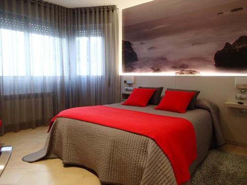 a bedroom with a large bed with red pillows at Hotel Vila da Guarda in A Guarda