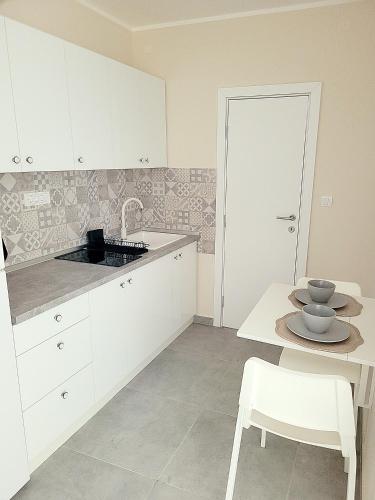 a kitchen with white cabinets and a table with a bowl on it at Oaza apartmani 2 in Senta