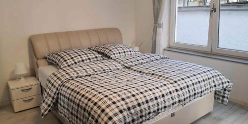 ein Bett mit einer karierten Decke und Kissen in einem Schlafzimmer in der Unterkunft Traumhafte Ferienwohnung mit drei Schlafzimmer in Biebrich
