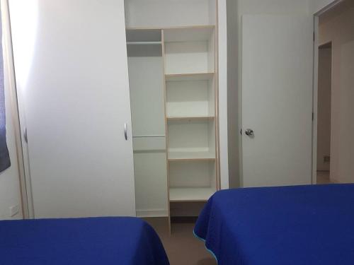a bedroom with a blue bed and white shelves at Depto con internet y tv cable in Ovalle