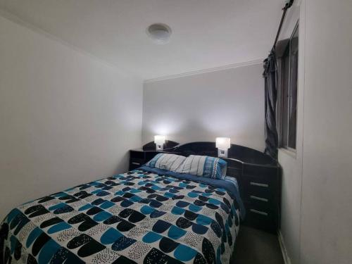 a bedroom with a bed with a blue and white comforter at Depto con internet y tv cable in Ovalle