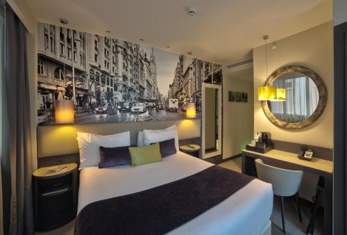 a hotel room with a bed and a desk and a mirror at Hotel Indigo Madrid - Gran Via, an IHG Hotel in Madrid