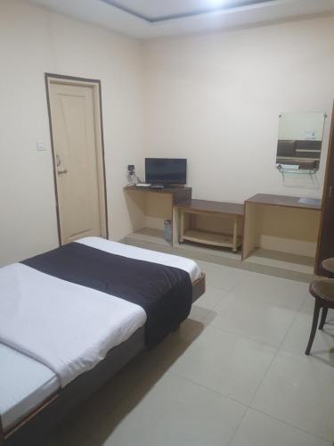 Dormitorio con cama, escritorio y TV en Hotel Anmol, en Ambikāpur