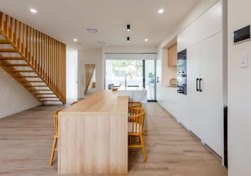 a kitchen with white walls and a wooden island with chairs at Unique Kirra townhouse in Gold Coast