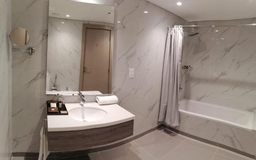 Gloria Hotel & Suites Doha في الدوحة: حمام مع حوض ودش وحوض استحمام