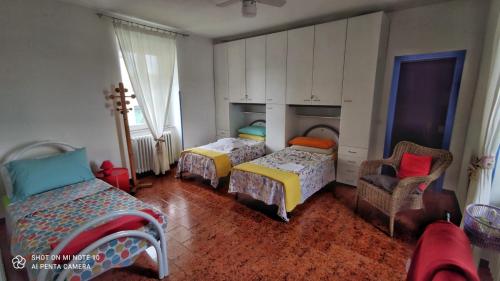 a bedroom with two beds and a chair at Da Simona- casa 4 posti letto + 4 aggiuntivi in Arona