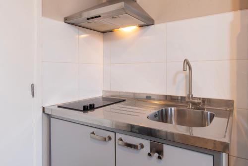 een keuken met een wastafel en een fornuis bij Blankebil Studios & Apartments in Zandvoort