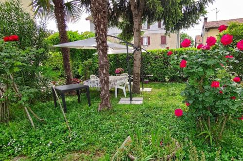 a garden with a table and an umbrella and roses at Da Simona- casa 4 posti letto + 4 aggiuntivi in Arona