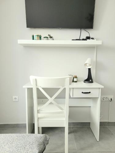 a white desk with a lamp and a tv on a wall at Oaza apartmani 3 in Senta