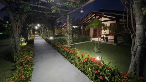 a garden with flowers and a walkway at night at POUSADA RANCHO PARAISO in Pôrto de Pedras