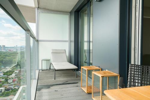 a balcony with a white chair and tables and glass windows at Vienna Residence, Marina Tower - Danube in Vienna
