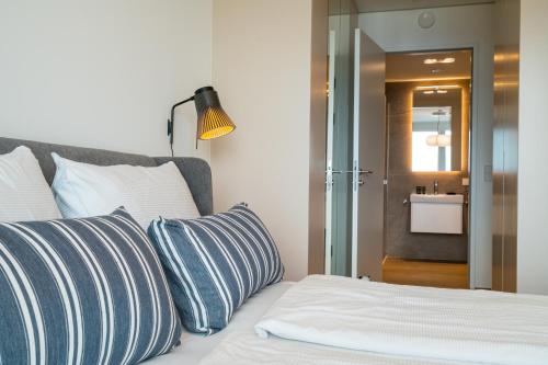 a bed with blue and white pillows and a bathroom at Vienna Residence, Marina Tower - Danube in Vienna
