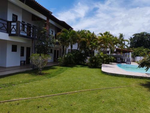 a yard of a house with a swimming pool and palm trees at Pousada São Nunca in Ilha de Comandatuba