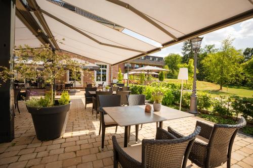 a patio with tables and chairs under an umbrella at Gut Altona in Dötlingen
