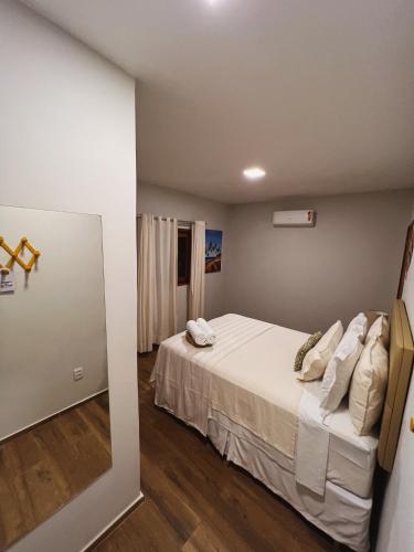 a bedroom with a bed with white sheets and a mirror at Beach Eco Stays Hotel Boutique Lagoinha in Tigre