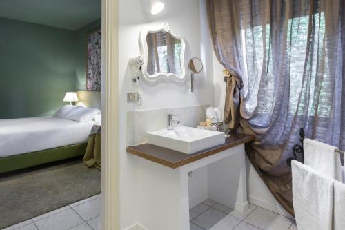 a bathroom with a sink and a bed and a mirror at B&B Maison Biagetti in Santarcangelo di Romagna