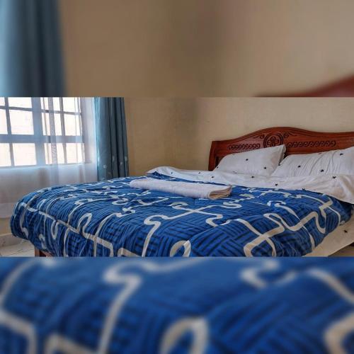Schlafzimmer mit einem Bett mit einer blauen und weißen Bettdecke in der Unterkunft Rubani homes in Nairobi