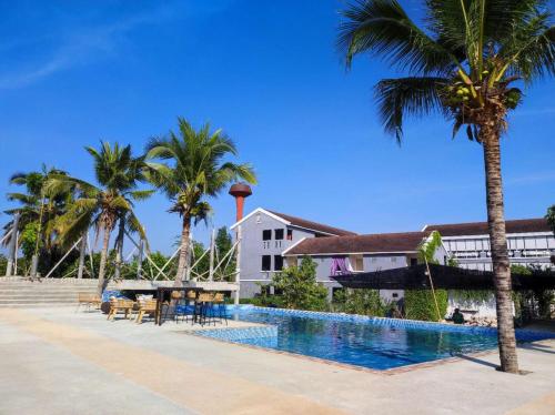 a swimming pool next to a building with palm trees at Home at 9 in Ban Klang (4)