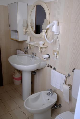 a bathroom with a sink and a mirror and a toilet at Hotel Il Canneto in Porto Ceresio